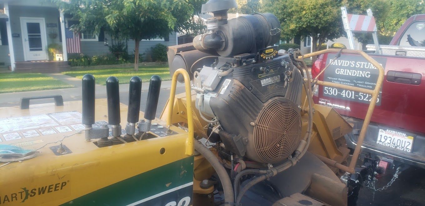 Yellow Vermeer Vanguard 35hp grinder parked behind a red Toyota Tundra with DAVID'S STUMP GRINDING on the tailgate